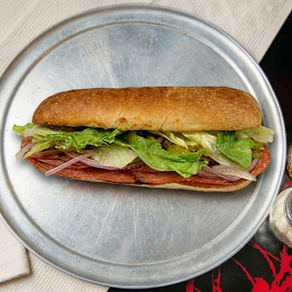 A salami and provolone sub sandwich with lettuce, onions, and peppers on a metal tray.